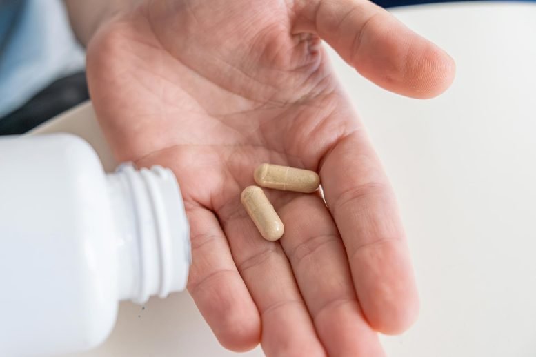 هذا السرد "Synbiotic" يتفوق على أوميغا 3 في مكافحة الالتهاب 3 رجل يسكب كبسولات المكملات الغذائية من فيتامين البروبيوتيك في يده