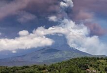 A view of Mount Etna erupting in June 2025. A large cloud of ash hangs over the volcano.