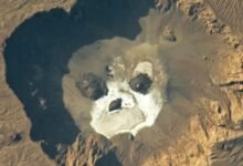 An astronaut photo of a volcanic caldera with a skull like shape