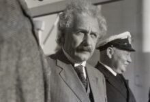 a black and white photo of Einstein standing in a line of men