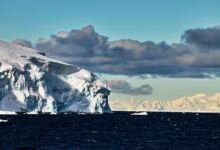 a photo of the edge of a glacier with ominous clouds in the background