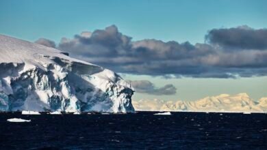 a photo of the edge of a glacier with ominous clouds in the background