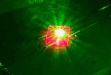 A picture of a pink, square-shaped crystal glowing with a neon green light