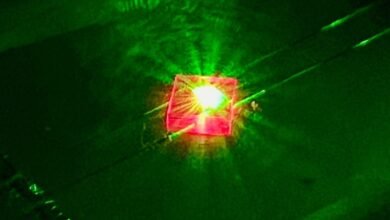 A picture of a pink, square-shaped crystal glowing with a neon green light