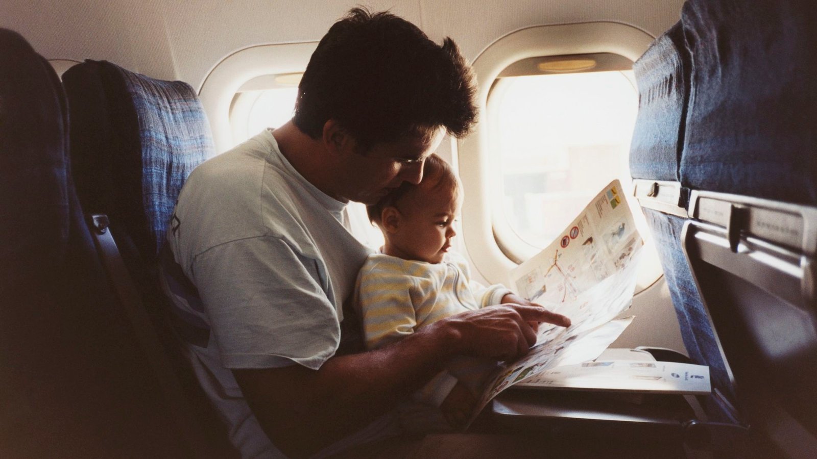 ما هو المقعد الأكثر أمانا على متن الطائرة؟ 3 a father hold his infant son on an airplane