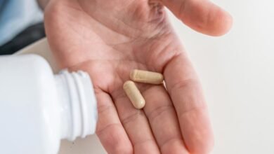 هذا السرد "Synbiotic" يتفوق على أوميغا 3 في مكافحة الالتهاب 5 رجل يسكب كبسولات المكملات الغذائية من فيتامين البروبيوتيك في يده