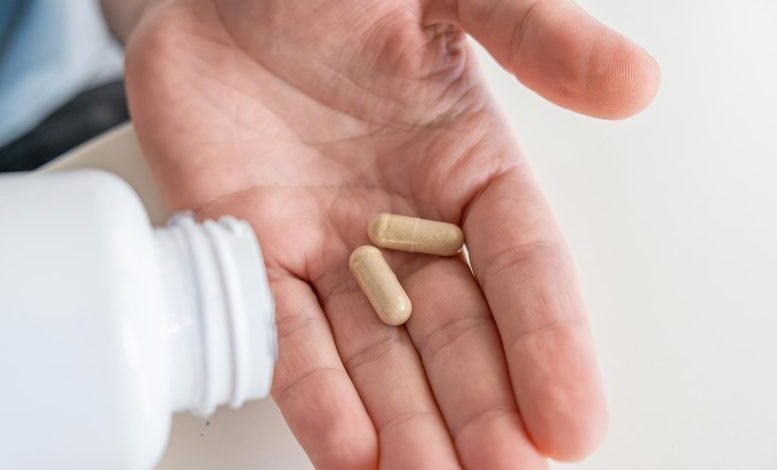 هذا السرد "Synbiotic" يتفوق على أوميغا 3 في مكافحة الالتهاب 1 رجل يسكب كبسولات المكملات الغذائية من فيتامين البروبيوتيك في يده