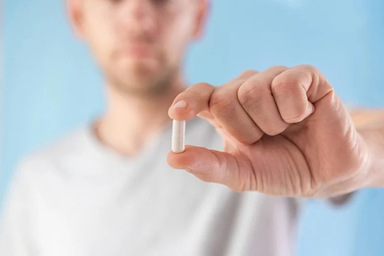 Man Holding White Capsule Supplement Pill