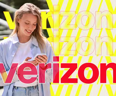 a woman smiling while using her phone with the verizon logo in the center