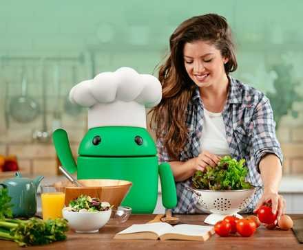 smiling woman preparing a salad in a kitchen beside the android mascot wearing a chef hat surrounded