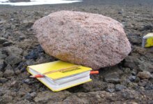 Pink Granite Boulder Next to a Yellow Notebook